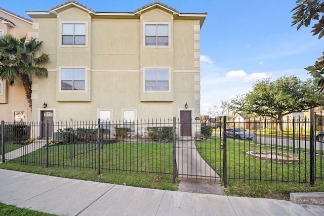 view of front facade with a fenced front yard, a front lawn, and stucco siding