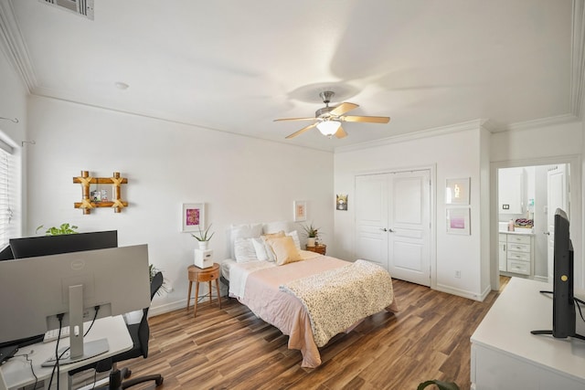 bedroom featuring baseboards, visible vents, wood finished floors, crown molding, and a closet