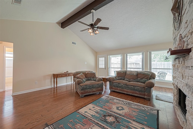 living room with a fireplace, visible vents, a textured ceiling, beamed ceiling, and hardwood / wood-style floors