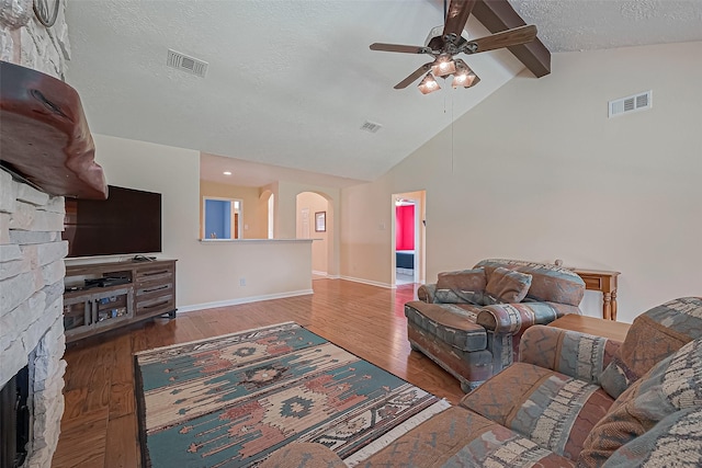 living room with arched walkways, a textured ceiling, wood finished floors, and visible vents