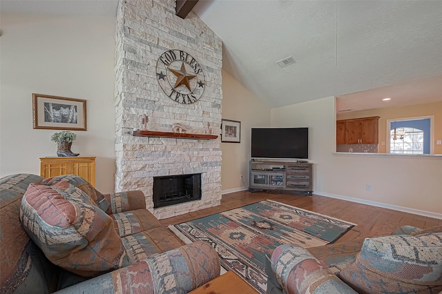 living room featuring visible vents, hardwood / wood-style floors, a stone fireplace, high vaulted ceiling, and baseboards