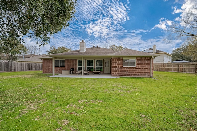 rear view of house with brick siding, a patio, and a fenced backyard