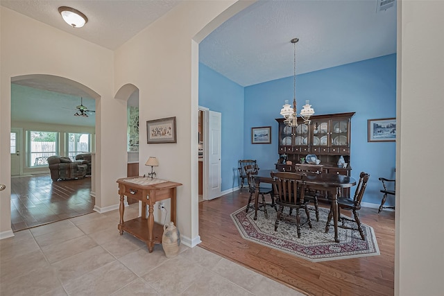 dining area featuring baseboards, arched walkways, wood finished floors, and ceiling fan with notable chandelier