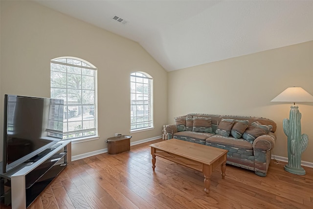 living room with lofted ceiling, baseboards, visible vents, and light wood finished floors