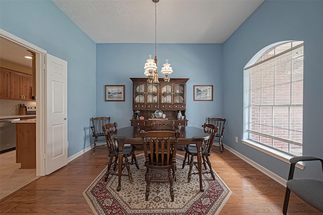 dining room with light wood-style floors, plenty of natural light, and an inviting chandelier