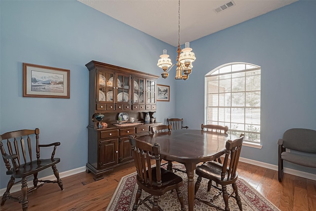 dining room featuring dark wood-style flooring, an inviting chandelier, visible vents, and baseboards