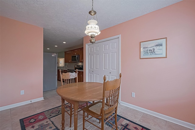 dining room featuring light tile patterned flooring, a textured ceiling, and baseboards