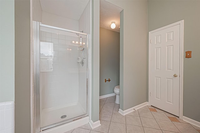 full bath with a textured ceiling, tile patterned flooring, toilet, baseboards, and a stall shower