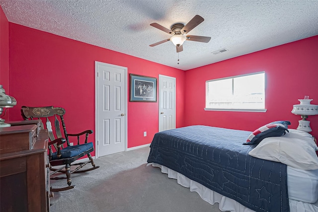 carpeted bedroom featuring a ceiling fan, visible vents, and a textured ceiling