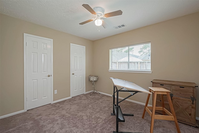 office space featuring carpet floors, visible vents, a ceiling fan, a textured ceiling, and baseboards