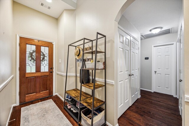 foyer entrance with visible vents, arched walkways, baseboards, and wood finished floors