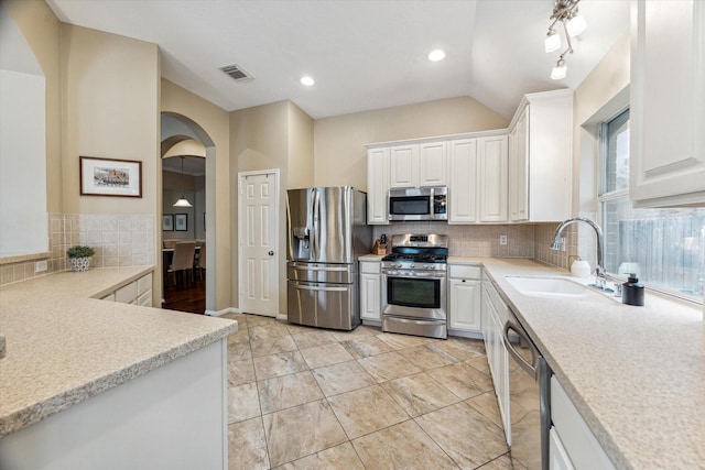 kitchen with visible vents, appliances with stainless steel finishes, arched walkways, white cabinets, and a sink