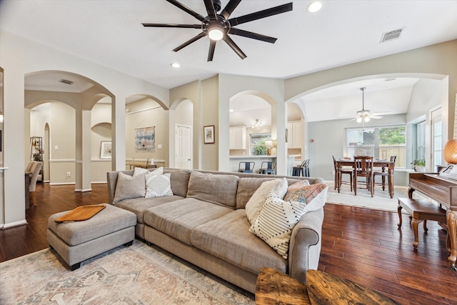 living area with hardwood / wood-style flooring, a ceiling fan, visible vents, and vaulted ceiling