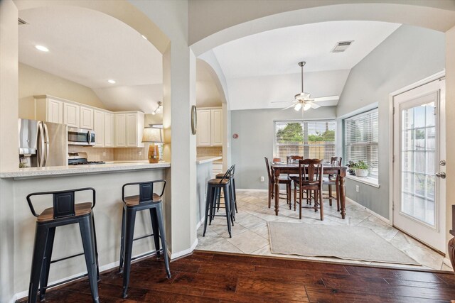 kitchen featuring visible vents, stainless steel appliances, arched walkways, lofted ceiling, and ceiling fan