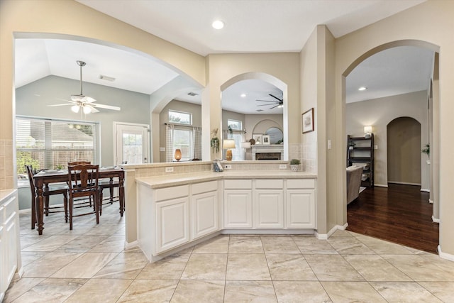 kitchen with a ceiling fan, light tile patterned flooring, white cabinets, light countertops, and vaulted ceiling