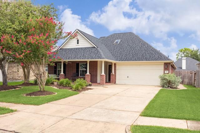 view of front facade featuring brick siding, an attached garage, concrete driveway, and a front yard