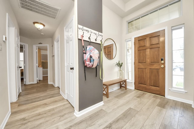 foyer with light wood-style flooring, visible vents, and baseboards