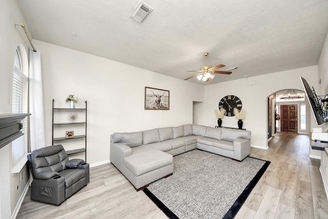 living room with baseboards, visible vents, arched walkways, a ceiling fan, and light wood-type flooring