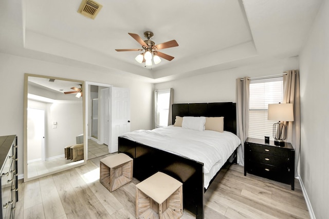 bedroom with a raised ceiling and light wood finished floors