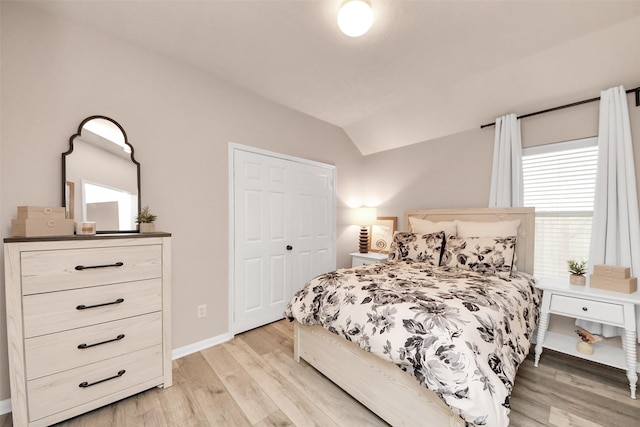 bedroom featuring lofted ceiling, a closet, light wood-style flooring, and baseboards