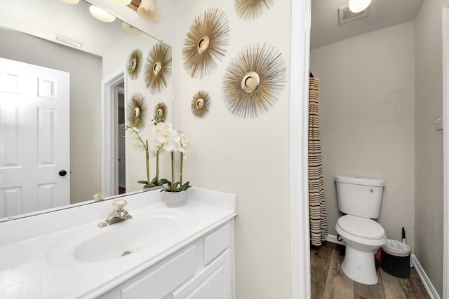 bathroom with visible vents, baseboards, toilet, wood finished floors, and vanity