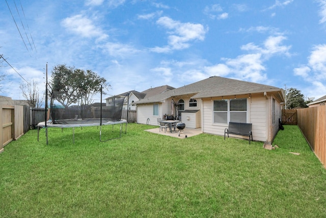 back of house featuring a patio area, a fenced backyard, a trampoline, and a lawn