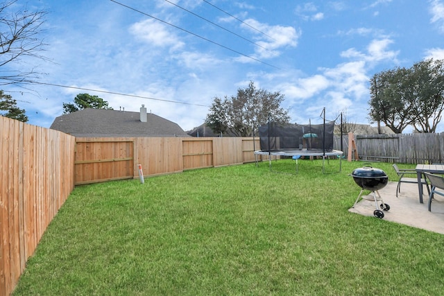 view of yard featuring a trampoline, a patio area, and a fenced backyard