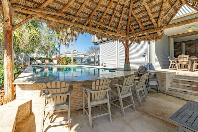 view of patio featuring a fenced in pool, outdoor dry bar, and a gazebo