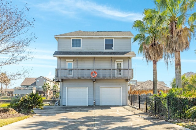 view of front of house with a garage, concrete driveway, and fence