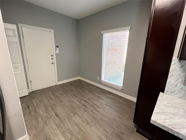 unfurnished room featuring a wealth of natural light, baseboards, and wood finished floors