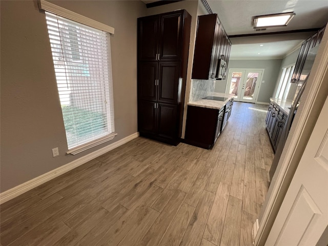 kitchen with baseboards, ornamental molding, french doors, light wood-type flooring, and stainless steel microwave