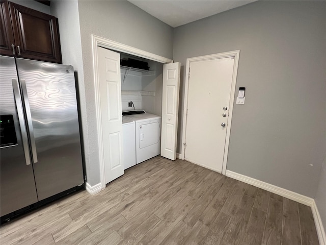 laundry area with laundry area, light wood-type flooring, washing machine and dryer, and baseboards