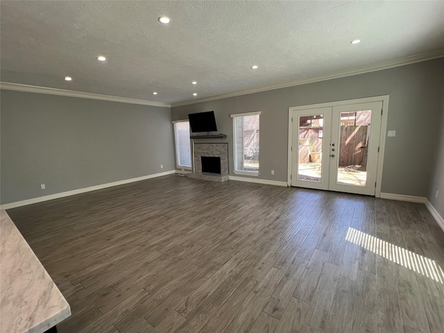 unfurnished living room featuring dark wood-style floors, french doors, a fireplace, a textured ceiling, and baseboards