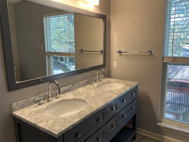 full bathroom with double vanity, baseboards, and a sink