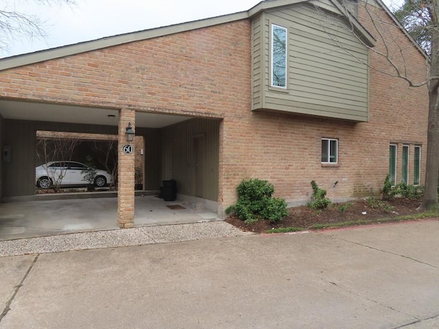 view of side of home featuring a garage, driveway, and brick siding