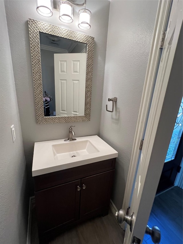 bathroom with a textured wall, wood finished floors, and vanity