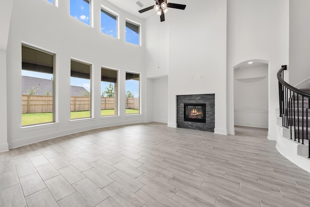 unfurnished living room with stairs, ceiling fan, and plenty of natural light