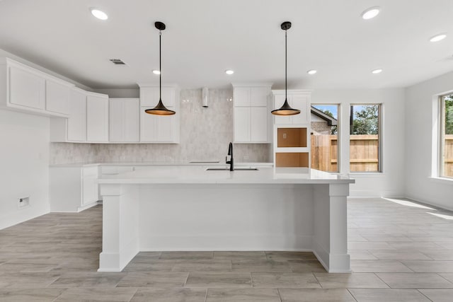 kitchen featuring white cabinetry, a sink, a large island, and decorative backsplash