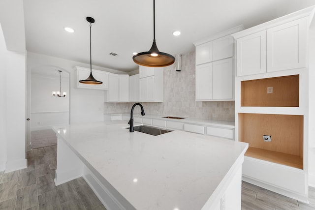 kitchen with a sink, visible vents, white cabinetry, a large island, and backsplash