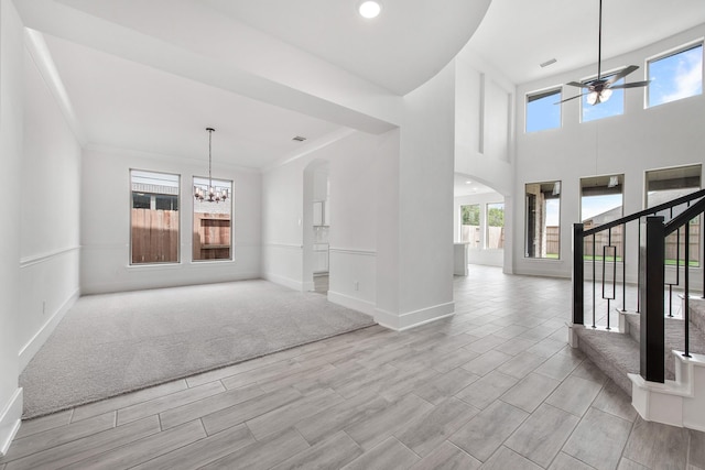 unfurnished room featuring arched walkways, recessed lighting, ceiling fan with notable chandelier, baseboards, and stairway