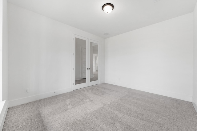 spare room featuring french doors, carpet flooring, and baseboards