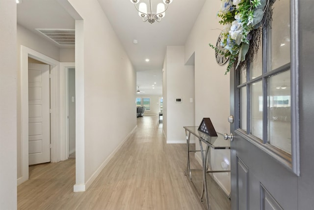 hallway featuring a chandelier, visible vents, light wood-style flooring, and baseboards