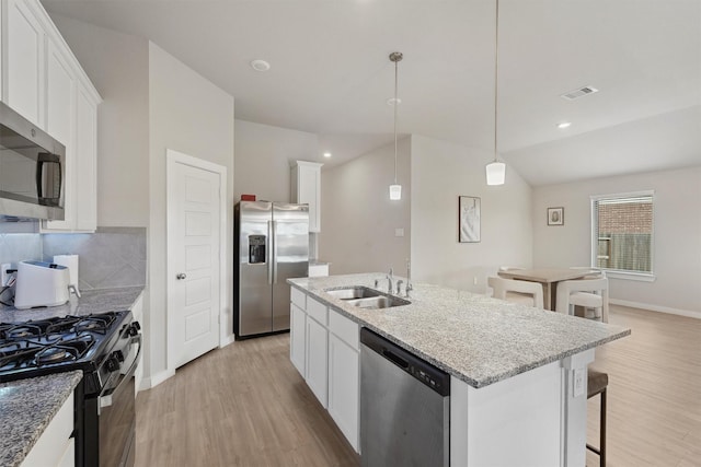 kitchen with visible vents, appliances with stainless steel finishes, a kitchen island with sink, light wood-type flooring, and a sink