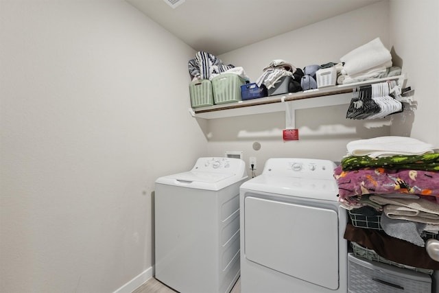 laundry room with laundry area, baseboards, separate washer and dryer, and wood finished floors