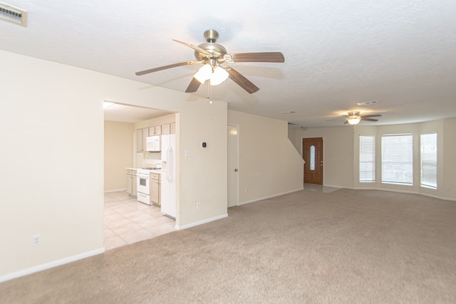 unfurnished living room featuring a ceiling fan, visible vents, light colored carpet, and a textured ceiling