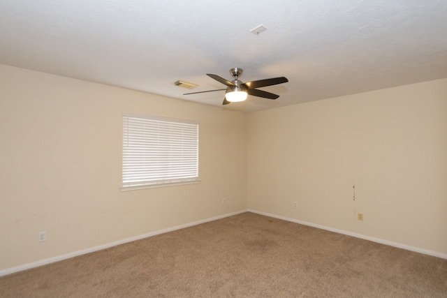 spare room featuring baseboards, visible vents, a ceiling fan, and light colored carpet