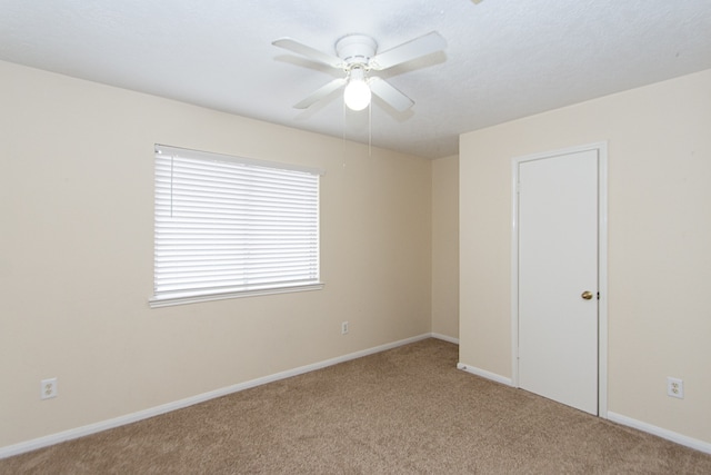 spare room featuring carpet floors, ceiling fan, and baseboards