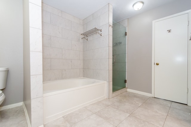 bathroom featuring tile patterned flooring, toilet, baseboards, a shower stall, and a tub