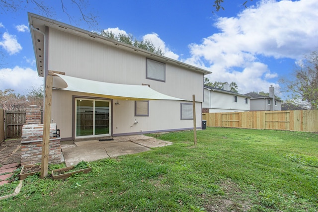 rear view of property featuring a yard, a fenced backyard, and a patio