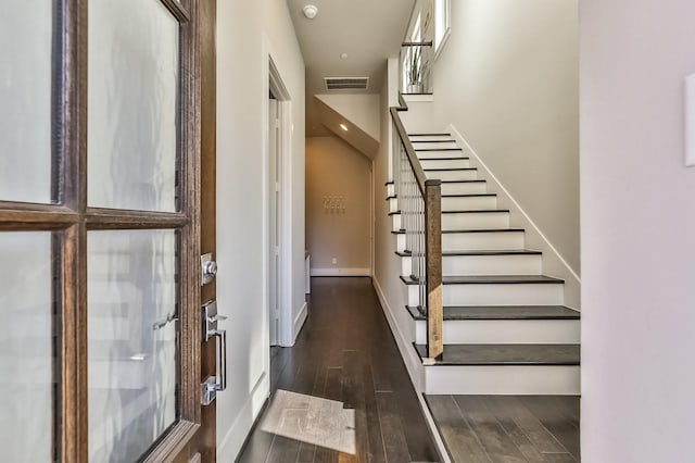 staircase featuring visible vents, baseboards, and wood finished floors